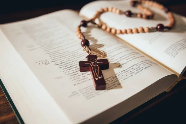 the wooden cross over opened bible on wooden table. Beautiful background