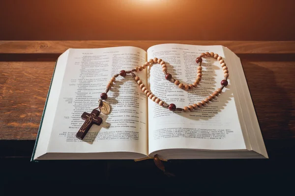 the wooden cross over opened bible on wooden table. Beautiful background