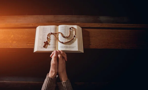 基督教妇女在教堂祈祷 双手交叉 木桌上有圣经 — 图库照片