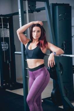 Spor salonunda egzersiz yapan güzel bir genç bayan. Kaslı vücutlu genç bir kadın. Fitness konsepti.