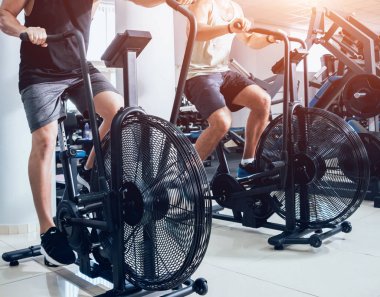 Kas vücut kardiyo egzersiz için hava bisiklet kullanarak genç erkeklerle eğitim spor salonu çapraz. Fitness kavramı.