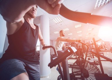 Kas vücut kardiyo egzersiz için hava bisiklet kullanarak genç erkeklerle eğitim spor salonu çapraz. Fitness kavramı.