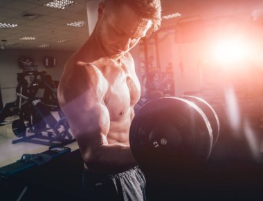 Yakışıklı, kaslı bir adam, halterlerle çalışıyor, fitness konsepti.