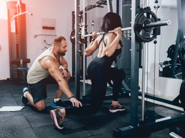 Spor salonunda fitness eğitmeni ile egzersiz yapan kadın.