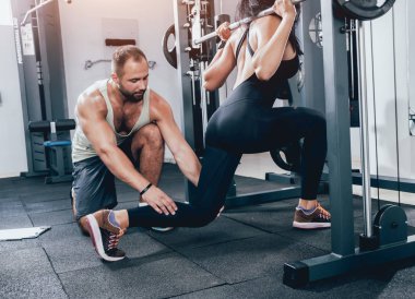 Spor salonunda fitness eğitmeni ile egzersiz yapan kadın.