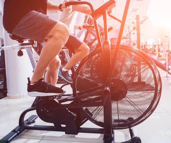 年轻男子与肌肉发达的身体使用空中自行车有氧运动在交叉训练健身房锻炼 健身理念 — 图库照片