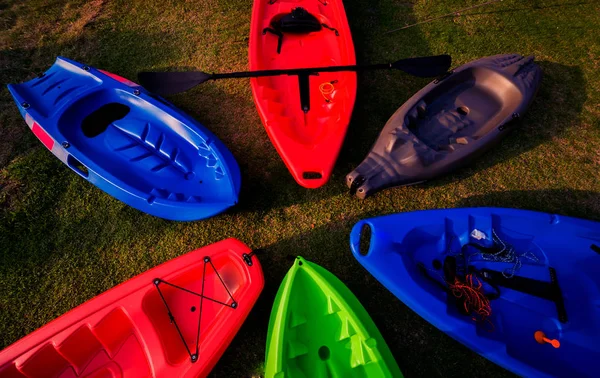 Group of canoes and kayaks on a green grass. Background