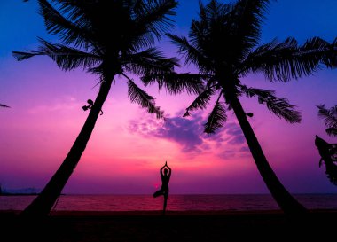 Güzel ve genç birbayan practic yoga sahilde. Sabah egzersiz. Güneş doğuyor. Avuç içi arka plan