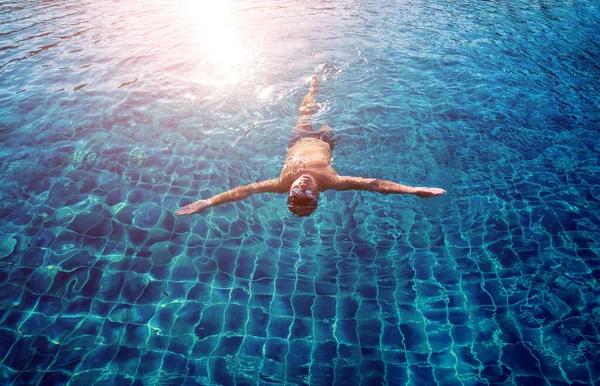 Young athletic man swimming in swimming pool, active sport concept