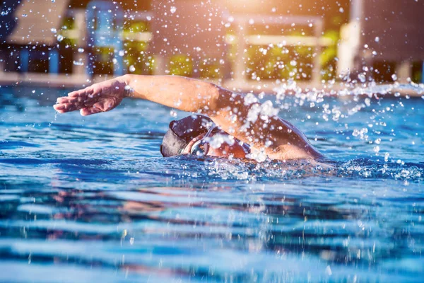 Young athletic man swimming in swimming pool, active sport concept