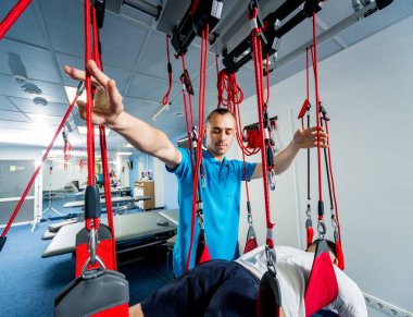 Uzaklaştırma eğitim terapisi. Genç adam süspansiyon temelli egzersiz sistemiyle fitness çekiş terapisi yapıyor.