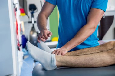 Rehabilitasyon merkezinde genç bir erkek hastayla birlikte çalışan fizyoterapistin kapanışı.