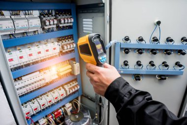 Fünye kutusundaki sıcaklığı kontrol etmek için kızılötesi termal görüntüleme kamerası kullanan teknisyenleri kapat