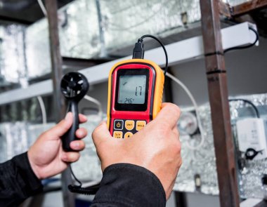 Teknisyen, hava akışı ölçümlerini elle ölçen anemometre kullanıyor