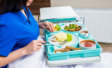 Hastanede yemek yiyen genç bir kadın, hasta için kahvaltı tepsisi.