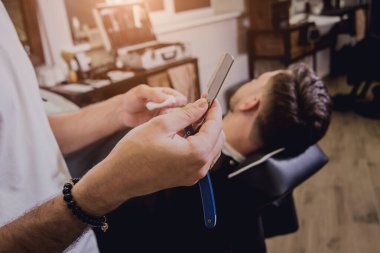 Berber dükkanında son moda saç kesimi olan genç bir adam. Berber saç ve sakal kesimi yapıyor. Berber dükkanı kavramı.