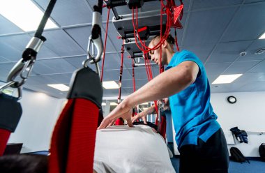 Uzaklaştırma eğitim terapisi. Genç adam süspansiyon temelli egzersiz sistemiyle fitness çekiş terapisi yapıyor.