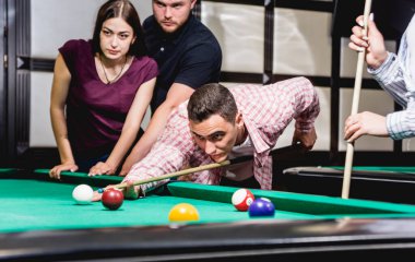 Bilardo oynayan bir grup neşeli genç arkadaş. İşten sonra eğlenceli zamanlar.