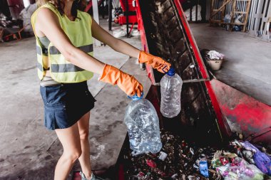 Woman-volunteer sorting trash at modern recycling plant