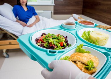 Hastanede yemek yiyen genç bir kadın, hasta için kahvaltı tepsisi.