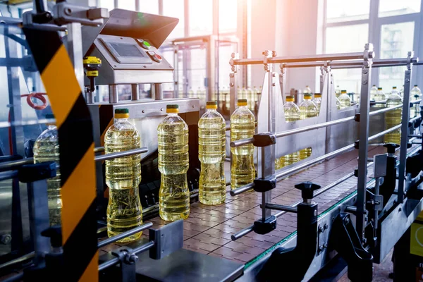 Bottling line of sunflower oil in bottles at plant, high technology concept, industrial background