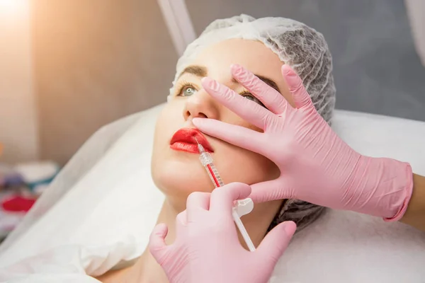 De arts cosmetoloog maakt de gezichtsinjecties procedure. Jonge vrouw in een schoonheidssalon. — Stockfoto
