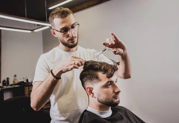 理容室で流行の散髪をしている若い男 理髪師は髪とひげのトリムを行います コンセプト Barbershop — ストック写真