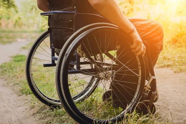 Kamp alanında arkadaşlarıyla dinlenen engelli bir adam. Çadırların arka planında, ormanda tekerlekli sandalye. Kamp yapmak. Yaz zamanı.