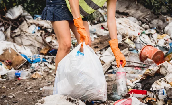 Woman volunteer helping clean field of plastic garbage. Earth day and ecology concept