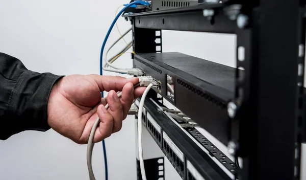 close up of technician connecting network cables to switches