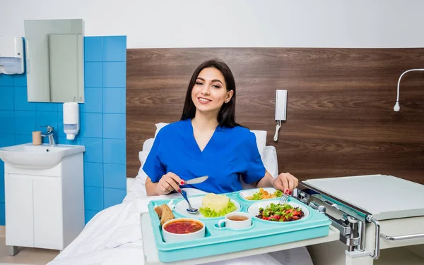 young woman eating in hospital, tray with breakfast for patient