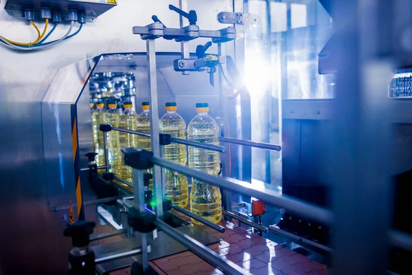 Bottling line of sunflower oil in bottles at plant, high technology concept, industrial background