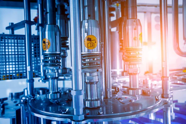 Otomatik doldurma makinesi plastik şişelere su dolduruyor, endüstriyel arka plan