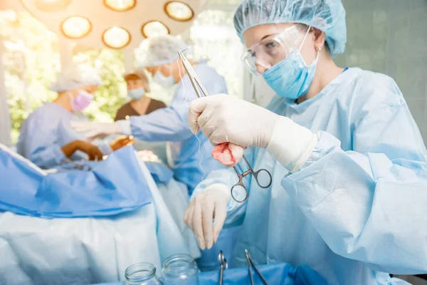 Хірург і помічники в операційній кімнаті з хірургічним обладнанням . — стокове фото