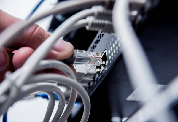 close up of technician connecting network cables to switches
