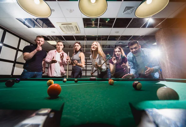 Bilardo oynayan bir grup neşeli genç arkadaş. İşten sonra eğlenceli zamanlar.