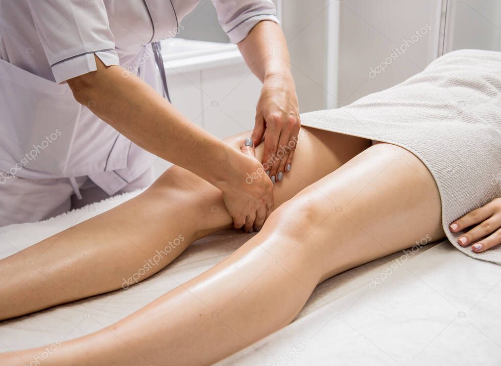 Beautiful young woman enjoying legs massage in spa salon. Cosmetology concept