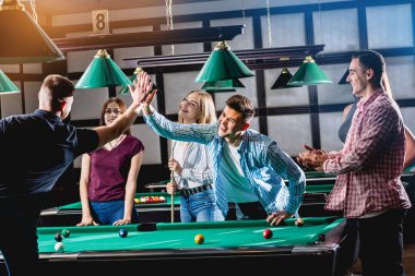 Bilardo oynayan bir grup neşeli genç arkadaş. İşten sonra eğlenceli zamanlar.