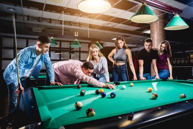Bilardo oynayan bir grup neşeli genç arkadaş. İşten sonra eğlenceli zamanlar.