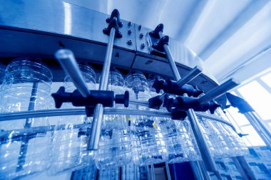 Otomatik doldurma makinesi plastik şişelere su dolduruyor, endüstriyel arka plan