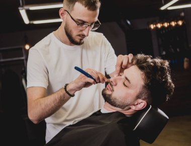 Berber dükkanında son moda saç kesimi olan genç bir adam. Berber saç ve sakal kesimi yapıyor. Berber dükkanı kavramı.