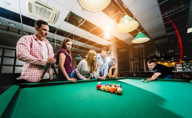 Bilardo oynayan bir grup neşeli genç arkadaş. İşten sonra eğlenceli zamanlar.