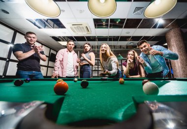 Bilardo oynayan bir grup neşeli genç arkadaş. İşten sonra eğlenceli zamanlar.