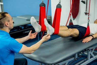 Uzaklaştırma eğitim terapisi. Genç adam süspansiyon temelli egzersiz sistemiyle fitness çekiş terapisi yapıyor.