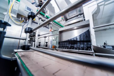 Otomatik doldurma makinesi plastik şişelere su dolduruyor, endüstriyel arka plan