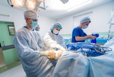 Artroskop ameliyatı. Modern artroskopik aletlerle ameliyathanede takım çalışması yapan ortopedik cerrahlar. Diz ameliyatı. Hastane geçmişi