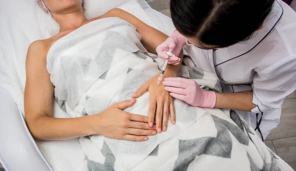 Il medico cosmetologo fa la procedura di iniezione delle braccia. Giovane donna in un salone di bellezza . — Foto Stock