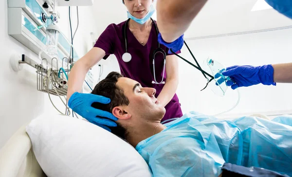 Los médicos dan reanimación a un paciente masculino en la sala de emergencias. Masaje cardíaco —  Fotos de Stock