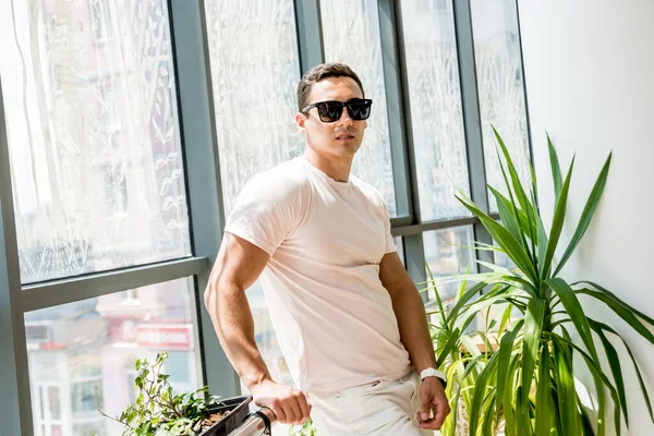 Pencereye poz veren gülümseyen genç adam portresi.