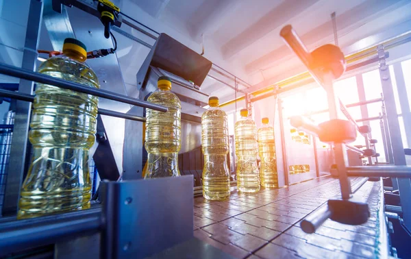 Bottling line of sunflower oil in bottles at plant, high technology concept, industrial background